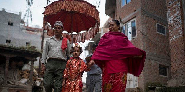 BHAKTAPUR, NEPAL - OCTOBER 07: The Kumari priest and his wife escort Jibika Bajracharya, the newly appointed child goddess Kumari, through the streets on October 7, 2016 in Bhaktapur, Nepal. The Bhaktapur Kumari is a living child goddess and is an ancient tradition in Kathmandu Valley as devotees worship the newly appointed child goddess in order to receive blessings from ancestors or deities. As the new Kumari of Bhaktapur, Jibika Bajracharya performs her role in public during the 15-day long D