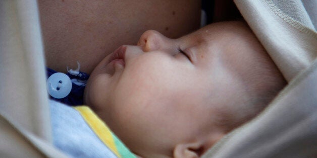 A baby sleeps in the arms of his mother after a mass breastfeeding in celebration of World Breastfeeding Week, in Thessaloniki, Greece Sunday, Nov. 3, 2013. Mothers breast fed their babies in the 4th Panhellenic public breastfeeding taking place simultaneously in 39 cities of Greece. About 550 lactating mothers took part . (AP Photo/Nikolas Giakoumidis)