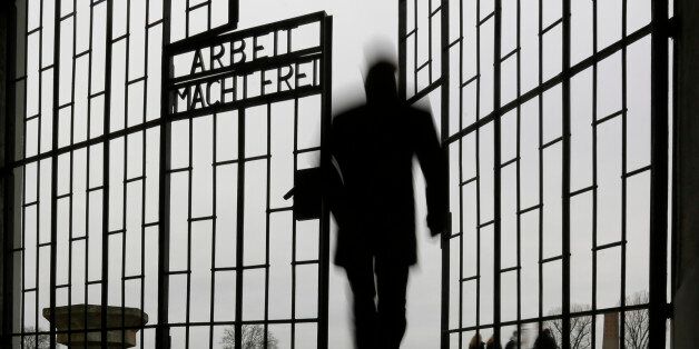 A man enters the Sachsenhausen Nazi death camp through the gate with the phrase 'Arbeit macht frei' (work...