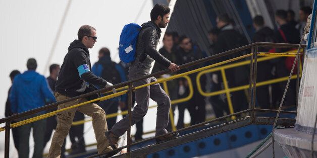 An officer from the European Unionâs border protection agency, Frontex, leads a migrant to board a ferry in the port of Mytilini, Lesbos island, Greece, on Friday, April 8, 2016. Amid protests, Greece Friday resumed deportations of refugees and migrants from its islands to Turkey after a four-day pause, sending back 124 people from Lesbos to a nearby port on the Turkish coast. (AP Photo/Petros Giannakouris)