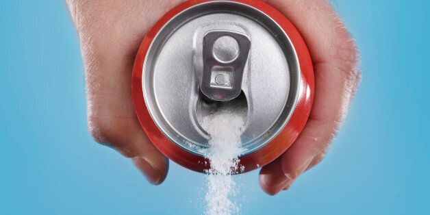 hand holding soda can pouring a crazy amount of sugar in metaphor of sugar content of a refresh drink isolated on blue background in healthy nutrition, diet and sweet addiction concept