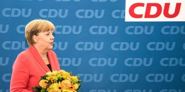 German Chancellor Angela Merkel prepares to offer flowers to the Christian Democratic Union's (CDU) main candidate in regional elections in Berlin during a meeting of the party leadership one day after regional elections at the CDU headquarters in Berlin on 19 September, 2016.German Chancellor Angela Merkel's party on Monday digested another stinging poll loss, in Berlin state elections, and the relentless rise of the upstart AfD which rails against her liberal refugee policy. / AFP / John MACDOUGALL (Photo credit should read JOHN MACDOUGALL/AFP/Getty Images)