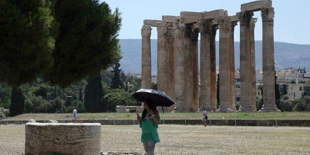A tourist holds an umbrella to protect from the sun as she visits the Temple of Zeus in Athens, Tuesday, July 7, 2015. This is Greek tourism - July 2015 style - as the peak summer season in one of the worldâs most popular destinations is glitched by a financial crisis of frightening proportions. The World Travel and Tourism Council said tourismâs direct contribution to the Greek economy was more than 29 billion euros in 2014, accounting for just over 17 percent of the countryâs GD