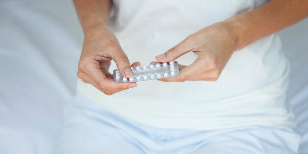 Woman holding birth control pills, mid section