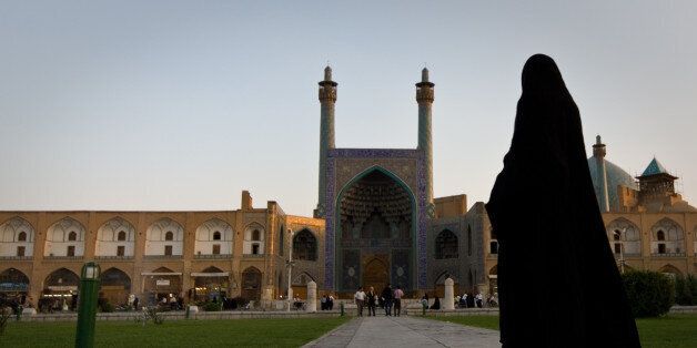 Iran woman walking in towards Shah mosque located in Naghsh i Jahan square in center of Isfahan, Iran.