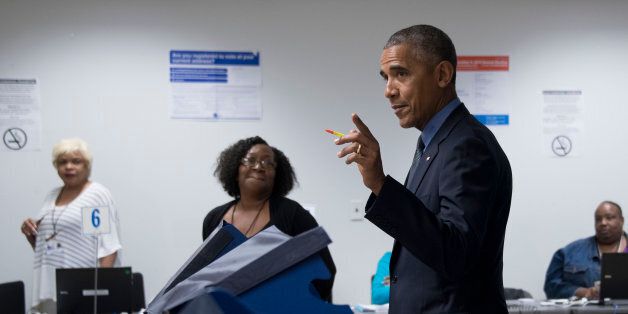 Poll workers look on as US President Barack Obama (C) gestures towards the press as he votes early at the Cook County Office Building in Chicago, Illinois, October 7, 2016.Obama cast an early ballot on Friday, highlighting a Democratic drive to get voters to the polls even before November 8. During an unannounced visit, Obama stood before a voting machine at the Chicago Board of Elections office, punched in his choice and smirked when asked who he had voted for. / AFP / JIM WATSON (Photo