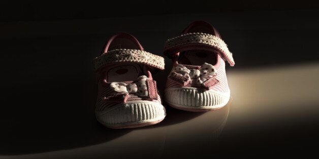 Conceptual image of violence to kids represented with a pair of baby shoes on a dark background