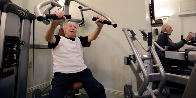 In this Thursday, March 24, 2016 photo, 100-year-old Samuel Bender, left, and 87-year-old Richard Forsyth, right, work out in a gym at Laurelmead Cooperative retirement community, in Providence, R.I. The wealthy retirement community has six centenarians. (AP Photo/Steven Senne)
