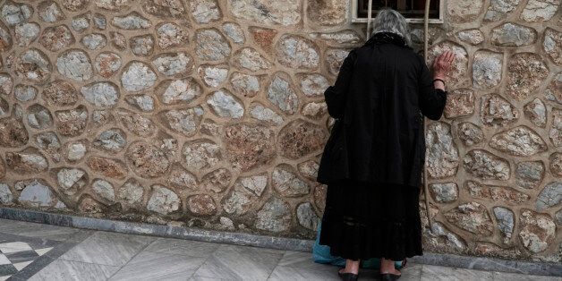 ATHENS, GREECE - APRIL 29: Woman praying outside of the church window during the epitaph procession on Good Friday at St. Isidore church in the 2nd Cemetery of Athens on April 29, 2016 wich form a key part of Orthodox easter. (Photo by Angeliki Panagiotou/Corbis via Getty Images)