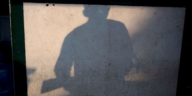 In this Thursday, Jan. 16, 2014 photo, the shadow of an armed man, who belongs to the Self-Defense Council of Michoacan, (CAM), is cast on a wall at a checkpoint set up by the self-defense group at the entrance of Antunez, Mexico. Vigilantes in violent Michoacan state insist they won't lay down their guns until top leaders of a powerful drug cartel are arrested, defying government orders as federal forces try to regain control in a lawless region plagued by armed groups. (AP Photo/Eduardo Verdugo)