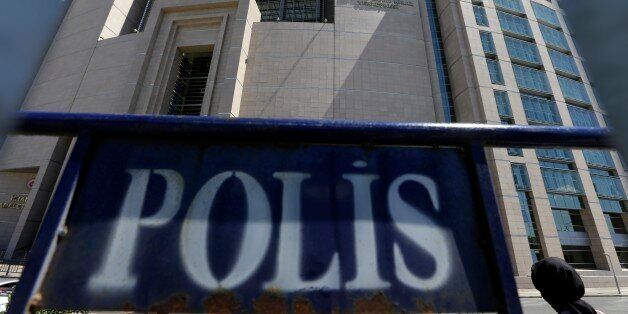 A woman enters a courthouse as a police fence is on display outside the building in Istanbul, on Monday, Aug. 15, 2016. Turkey's state-run news agency says police teams are conducting operations at three Istanbul courthouses as part of an investigation into the July 15 abortive coup. (AP Photo/Thanassis Stavrakis)