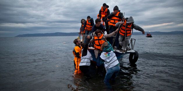In this Thursday, Dec. 3, 2015 photo, volunteers help refugees disembark from a vessel carrying Yazidi refugee Samir Qasu, 45, from Sinjar, Iraq, and his wife Bessi, 42, their two daughters Delphine, 18, seen center left, Dunia 13, and their two sons Dilshad, 17, seen center left, and Dildar, 10, as it arrives to the northeastern Greek island of Lesbos from the Turkish coast. (AP Photo/Muhammed Muheisen)