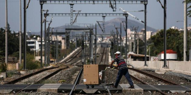 A man pushes a cart as he crosses railways at Rentis suburb in Athens, on Saturday, July 9, 2016. Staff of Greek Railways Organisation stage a five-day strike until next Tuesday opposing government's privatization plans. (AP Photo/Yorgos Karahalis)
