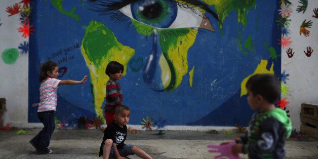 In this photo taken on Tuesday, Sept. 13, 2016, children play in front of a mural at Ritsona refugee camp north of Athens. Most of the people at the camp arrived in Greece in March, crossing to Lesbos and Chios just ahead of an agreement between the EU and Turkey that took effect. Under the deal, anyone arriving on Greek islands from Turkey on or after March 20 would be held on the island and face being returned to Turkey. Balkan countries began restricting crossings of their borders in early 2016, and shut them completely in early March, stranding tens of thousands of people in Greece. (AP Photo/Petros Giannakouris)