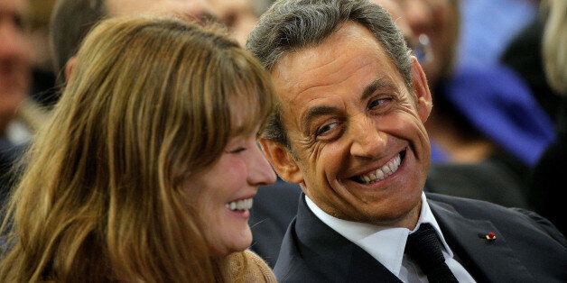 Former French President Nicolas Sarkozy, right, and his wife, Carla Bruni-Sarkozy, smile, during a meeting for the leadership of the conservative UMP party, in Paris, Friday, Nov. 7, 2014. Sarkozy, who drifted into the political wilderness after losing to Hollande in 2012, is seeking the leadership of the conservative UMP party. (AP Photo/Thibault Camus)