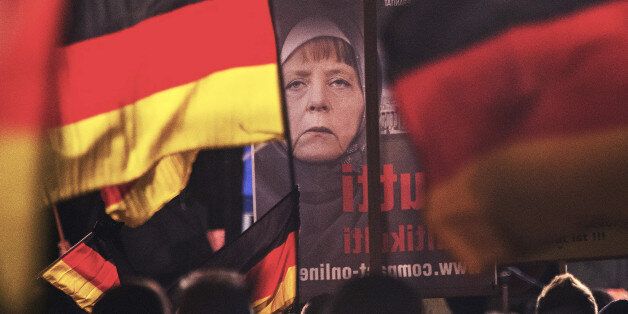 A banner depicting a manipulated image of German Chancellor Angela Merkel is carried by a protester during a demonstration initiated by the Alternative for Germany (AfD) party against what they call the uncontrolled immigration and asylum abuse in Erfurt, central Germany, Wednesday, Nov. 18, 2015. (AP Photo/Jens Meyer)