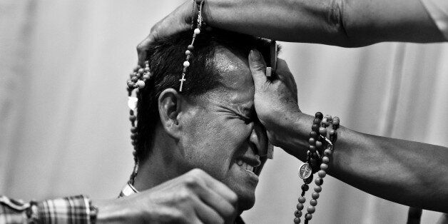 BOGOTA, COLOMBIA - MARCH 10: A Colombian pastor, pressing a crucifix on a believer's head, attempts to evict a supposed demon during the exorcism ritual performed at a house church on March 10, 2016 in Bogota, Colombia. Hundreds of Christian belivers, joined in nameless groups, gather every week in unmarked home churches dispersed in the city outskirts, to carry out prayers of liberation and exorcism. (Photo by Jan Sochor/Latincontent/Getty Images)