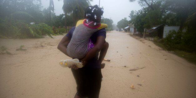 A woman and a child walk in a waterlogged street as they head to a shelter under the pouring rain caused by Hurricane Matthew, in Leogane, Haiti. Tuesday, Oct. 4, 2016. Matthew slammed into Haiti's southwestern tip with howling, 145 mph winds tearing off roofs in the poor and largely rural area, uprooting trees and leaving rivers bloated and choked with debris. (AP Photo/Dieu Nalio Chery)