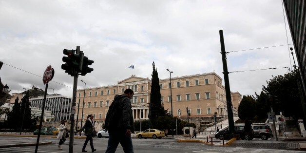 People make their way in front of the parliament in Athens, Monday, Feb. 23, 2015. Greece will present a list of proposed reforms to debt inspectors on Monday to get final approval for an extension to its rescue loans. But already the government was facing dissent within its ruling party over claims it is backtracking on its promise to ease budget cuts for the recession-battered Greeks. (AP Photo/Yorgos Karahalis)