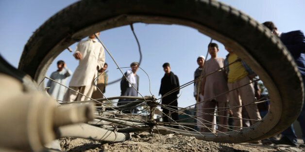Afghan civilians watch a damaged bicycle after a bomb explosion targeted an army vehicle in Kabul, Afghanistan, Monday, Oct. 3, 2016, A police said an Afghan soldier was killed in the bicycle bomb blast. (AP Photo/Rahmat Gul)