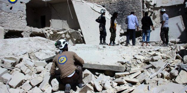 This photo provided by the Syrian Civil Defense group known as the White Helmets, shows members of Civil Defense inspecting damaged buildings after airstrikes hit the Bustan al-Qasr neighborhood of Aleppo, Syria, Sunday, Sept. 25, 2016. A broad coalition of Syrian rebels denounced international negotiations for peace as