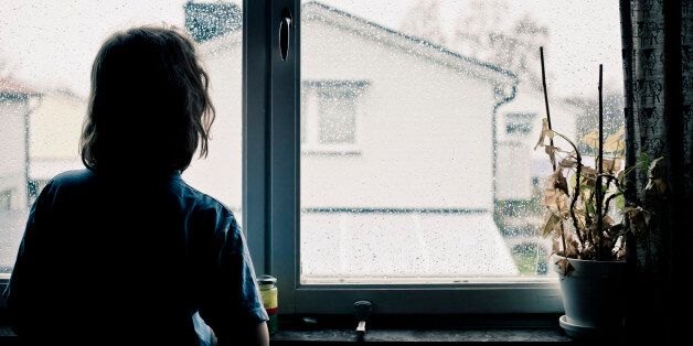 Girl looking through window on a rainy day