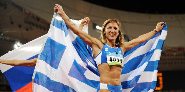 Greece's Hrysopiyi Devetzi celebrates with the Greek flag after winning the bronze medal in the women's triple jump in the National Stadium at the Beijing 2008 Olympics in Beijing, Sunday, Aug. 17, 2008. (AP Photo/Mark J. Terrill)