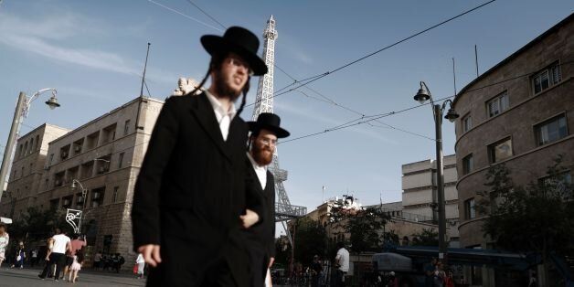 TOPSHOT - Two Ultra-Orthodox Jewish men walk past a replica of France's Eiffel Tower on display in the main street of downtown Jerusalem, on May 22, 2016. / AFP / THOMAS COEX (Photo credit should read THOMAS COEX/AFP/Getty Images)