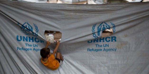 A child play in front of a UNHCR plastic sheet at Ritsona refugee camp, north of Athens, which hosts about 600 refugees and migrants on Thursday, Sept. 8, 2016. The refugee crisis is expected to be a central issue in discussions Friday at a meeting in Athens of leaders from Mediterranean countries in the European Union. (AP Photo/Petros Giannakouris)