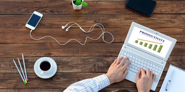 Natural Rough Wooden Desk and Man Working on Computer Top View Smart Casual Clothing Typing on Keyboard with Productivity Chart on Screen Smart Phone and Cup of Coffee aside