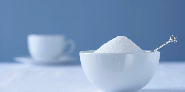 Bowl of sugar on table, tea cup in background