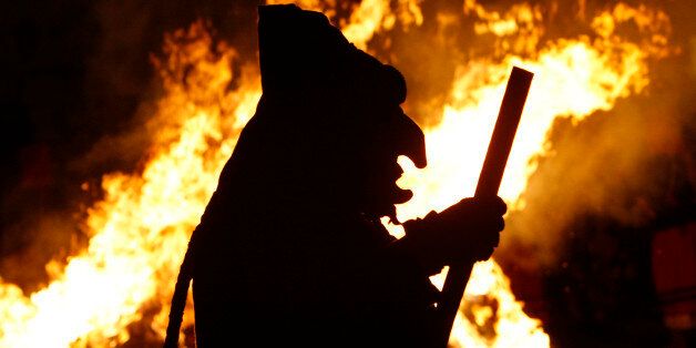 A reveler wearing a witch costume dances in front of a burning straw effigy in Offenburg, southwestern Germany, Tuesday, Feb. 24, 2009. The traditional burning off of a straw figure marks the end of the street carnival. (AP Photo/Thomas Kienzle)
