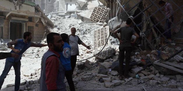 In this photo provided by the Syrian Civil Defense White Helmets, men stand amid rubble after airstrikes in al-Mashhad neighborhood in the rebel-held part of eastern Aleppo, Syria, Wednesday Sept. 21, 2016. Ibrahim Alhaj, a member of the volunteer first responders known as the Syria Civil Defense, said 24 people were killed in a series of bombings in several parts of the besieged city Aleppo on Wednesday. (Syrian Civil Defense White Helmets via AP)