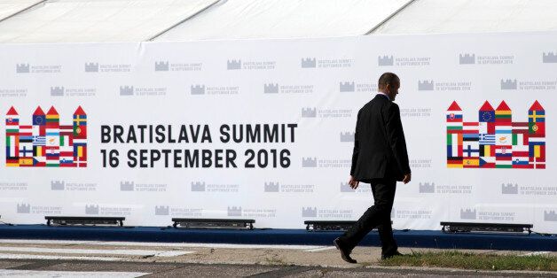 A journalist walks by the logo for an upcoming EU summit outside of the press center in Bratislava on Thursday, Sept. 15, 2016. An EU summit, without the participation of the United Kingdom, will kick off on Friday in Bratislava with discussions on the future of the EU following Brexit. (AP Photo/Virginia Mayo)