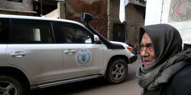 An elderly man stands along a street as he looks at an aid convoy of Syrian Arab Red Crescent and United Nation (UN) driving through the rebel held besieged city of Douma towards the besieged town of Kafr Batna to deliver aid, on the outskirts of Damascus, Syria February 23, 2016. Picture taken February 23, 2016. REUTERS/Bassam Khabieh