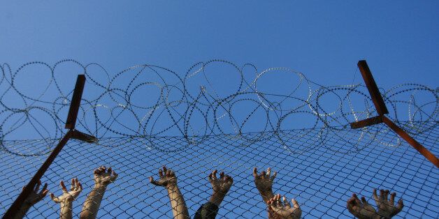 Immigrants lean on fences during unrest inside Pagani detention centre, in the eastern Aegean island of Lesvos, near the sea border line with Turkey October 19, 2009. The police has to cope with frequent unrest inside the overcrowded Pagani camp as the number of immigrants, around 800, exceeds the hosting capability of the center which was originally designed to hold about 250 people. REUTERS/John Kolesidis (GREECE)