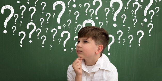 Little boy thinking surrounded question marks on chalkboard