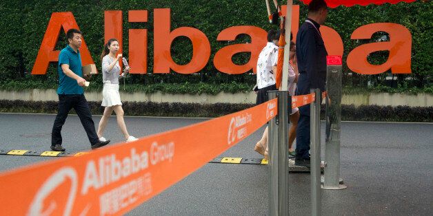 FILE - In this Friday, May 27, 2016, file photo, staffers pass security guards near a company logo at the Alibaba Group headquarters in Hangzhou, in eastern China's Zhejiang province. Alibaba reports financial results Thursday, Aug. 11. (AP Photo/Ng Han Guan, File)
