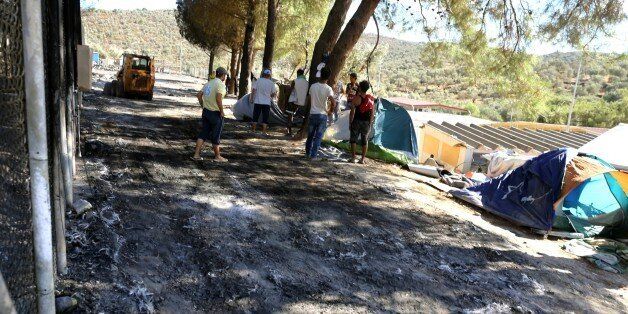 Workers clean the area after a fire gutted the camp following protests at the Moria refugee camp on the northeastern Greek island of Lesbos, on Tuesday, Sept. 20, 2016. Authorities of the island of Lesbos are calling for the immediate evacuation of thousands of refugees to the Greek mainland following the fire and nine migrants suspected of starting the blaze have been arrested, authorities said Tuesday. (Dimitris Tosidis/InTime News via AP)