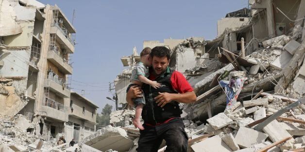 A Syrian man carries a baby after removing him from the rubble of a destroyed building following a reported air strike in the Qatarji neighbourhood of the northern city of Aleppo on September 21, 2016.Heavy bombardment pummelled Aleppo city and the wider province, key battlegrounds in Syria's conflict. The Syrian Observatory for Human Rights said dozens of raids hit the city's east overnight, as regime troops advanced on rebels in Aleppo's southwestern outskirts. / AFP / AMEER ALHALBI (Photo credit should read AMEER ALHALBI/AFP/Getty Images)
