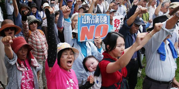 People raise their arms as they shout slogans during a rally after a judgment in a court in Naha, Okinawa prefecture, on September 16, 2016. The Japanese court approved the central government's plan to construct a US military base on Okinawa, though the drawn out legal dispute pitting Tokyo against the local government was expected to continue. / AFP / JIJI PRESS / STR / Japan OUT (Photo credit should read STR/AFP/Getty Images)