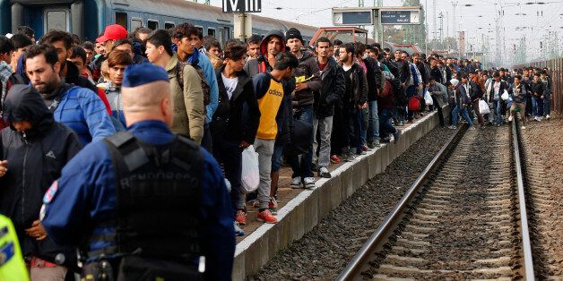 A Hungarian police officer watches as migrants arrive at the train station in Hegyeshalom, Hungary, October 6, 2015. Austria and Germany have committed to backing Greek efforts to secure more EU funds to cope with the influx and to boost staff on the ground. Many of the almost 400,000 migrants who have arrived in Greece this year have later passed through Austria on their way to Germany. REUTERS/Leonhard Foeger