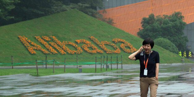 A woman talks on her phone near a company logo at the Alibaba Group headquarters in Hangzhou, in eastern China's Zhejiang province on Friday, May 27, 2016. Alibaba began 17 years ago in the modest living room of a gutsy man with a history of failure. Jack Ma struggled in school, and even Kentucky Fried Chicken refused to hire him. Today, Alibaba is a $15.7 billion e-commerce ecosystem that supports the livelihoods of tens of millions of merchants. Some 423 million shoppers last fiscal year picked through the billion listings that Alibaba's platforms host on any given day. (AP Photo/Ng Han Guan)