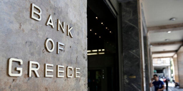 A visitor approaches the entrance to the headquarters of the Bank of Greece, the country's central bank, in Athens, Greece, on Monday, May 25, 2015. Even though no aid disbursements have been made since last summer, Greece has managed to meet external payments by slowing down spending, building up arrears to suppliers and vendors, encouraging citizens to pay overdue taxes, and seizing the cash reserves of regional governments, hospitals, universities, and other public entities. Photographer: Yorgos Karahalis/Bloomberg via Getty Images