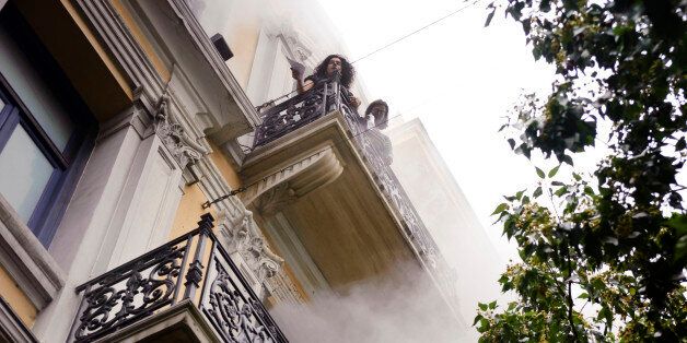 Bank employees, trapped by fire, look over the balcony ledge during an anti-government protest in central Athens, Wednesday, May 5, 2010. Three people died in the fire at the branch of Marfin Egnatia Bank, while the two women and two others were rescued. An estimated 100,000 people took to the streets Wednesday during a nationwide wave of strikes against spending cuts aimed at saving the country from bankruptcy (AP Photo/Iakovos Hatzistavrou) ** GREECE OUT **