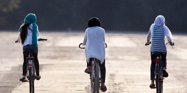 Three refugee girls ride their bikes over the tarmac of a former US military airport in Frankfurt, Germany, Friday, Sept. 9, 2016. (AP Photo/Michael Probst)