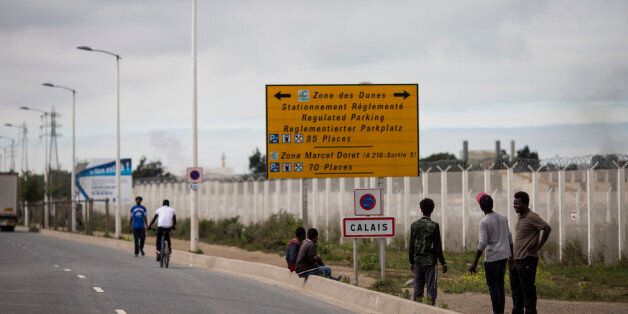 CALAIS, FRANCE - SEPTEMBER 06: Migrants by a Calais road sign outside the Jungle migrant camp on September 6, 2016 in Calais, France. The Jungle Books drop-in cafe for children at the Jungle is still facing closure and is embroiled in a legal battle with the French authorities. The cafe is run by volunteers and provides safe haven for up to 700 children living in the camp. Children attend language classes, are given free food and the opportunity to charge their mobile telephones so they can contact relatives in their homelands. Last month a French court rejected a bid by Calais authorities to demolish the Jungle Cafe and other makeshift shops and restaurants but the decision may be facing an appeal. (Photo by Jack Taylor/Getty Images)