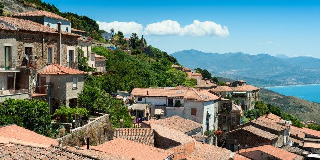 Roofs of old buildings on the hill with sea and mountains on background. This picture was taken in Acciaroli, Cilento park area, Campania, Italy.