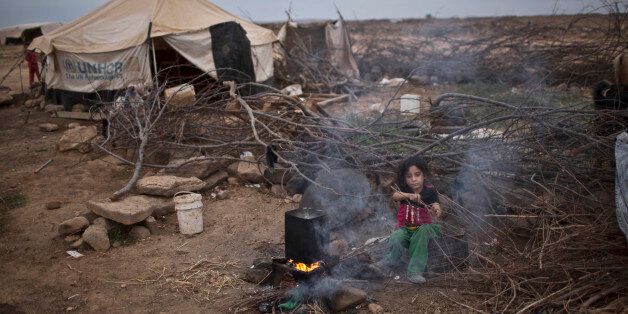 FILE -- In this Oct. 23, 2015 file photo, Syrian refugee Aysha Elwan, 5, helps her mother in breaking wood to be added under a fire to boil water outside her family's tent at an informal tented settlement near the Syrian border on the outskirts of Mafraq, Jordan. The number of Syrian refugees stranded in a remote desert area known as