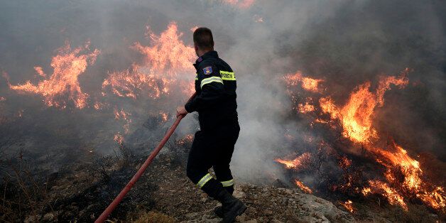 A firefighter tries to extinguish a forest fire near Keratea town, southeast of Athens July 12, 2014. REUTERS/Yorgos Karahalis (DISASTER ENVIRONMENT)